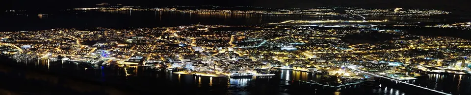 Vista panorámica invernal de la isla de Tromsø, el puente arqueado y las montañas nevadas del estrecho.