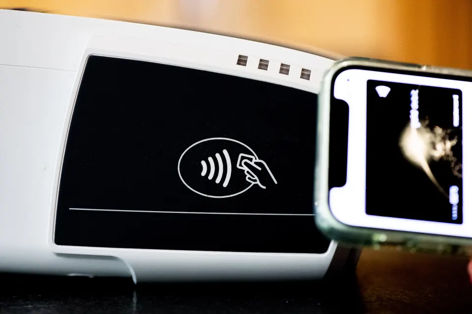 Viajero realizando un pago seguro mediante tecnología NFC en su teléfono móvil sobre un datáfono.