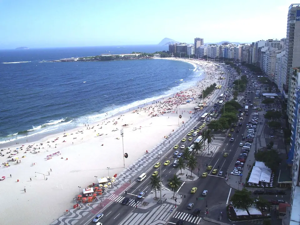 Extensa franja de arena dorada y el icónico paseo marítimo ondulado de la playa de Copacabana en Río de Janeiro.