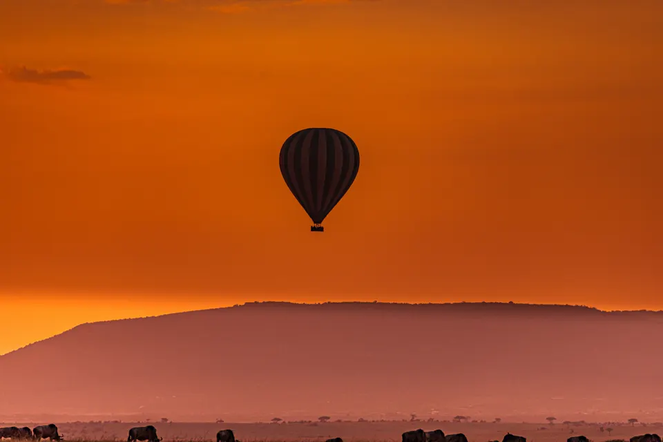 Vuelo en globo aerostático al amanecer sobrevolando las llanuras onduladas de la sabana en Kenia.