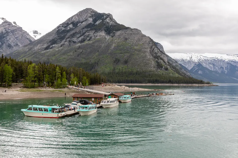 Embarcadero de madera y aguas profundas del Lago Minnewanka con las cumbres de las Rocosas Canadienses.