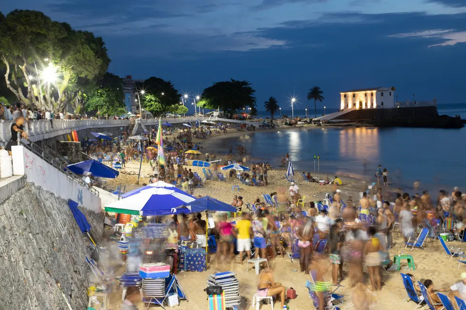 Aguas calmas y franja de arena de la playa de Porto da Barra con el Forte de Santa Maria en Salvador.