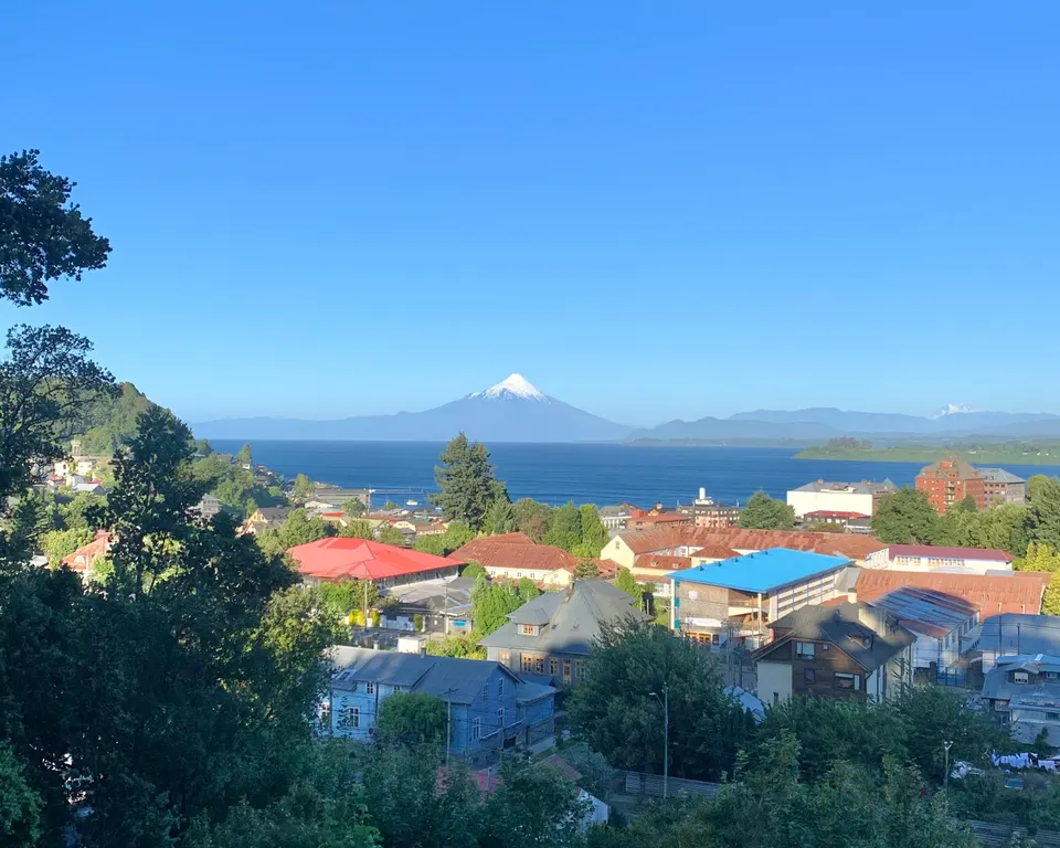 Paseo peatonal de la costanera de Puerto Varas con bancos de madera frente a las aguas mansas del lago Llanquihue