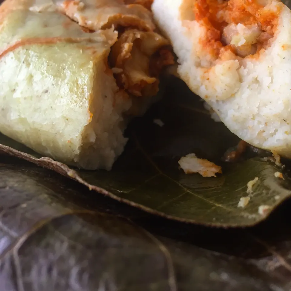 Chuchito tradicional guatemalteco de masa de maíz con salsa de recado envuelto en hojas secas de milpa.