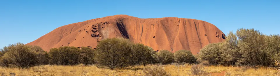 Sendero de circunvalación a pie junto a las texturas esculpidas por el viento en la base de Uluru.