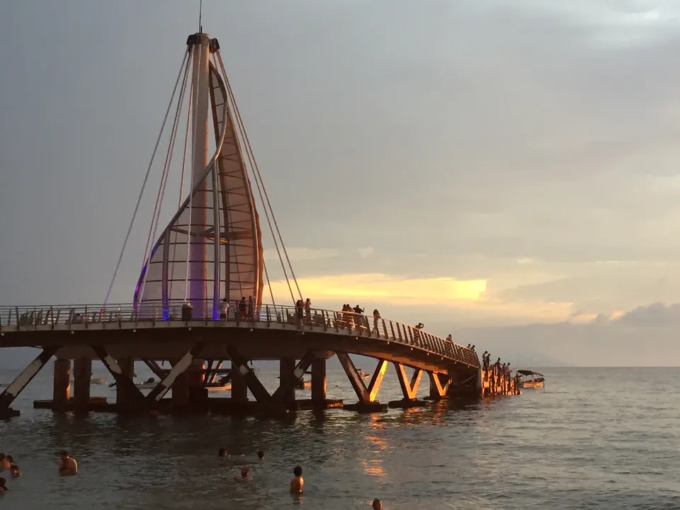 Icónico muelle en forma de vela iluminado sobre las olas en Playa Los Muertos, Puerto Vallarta.