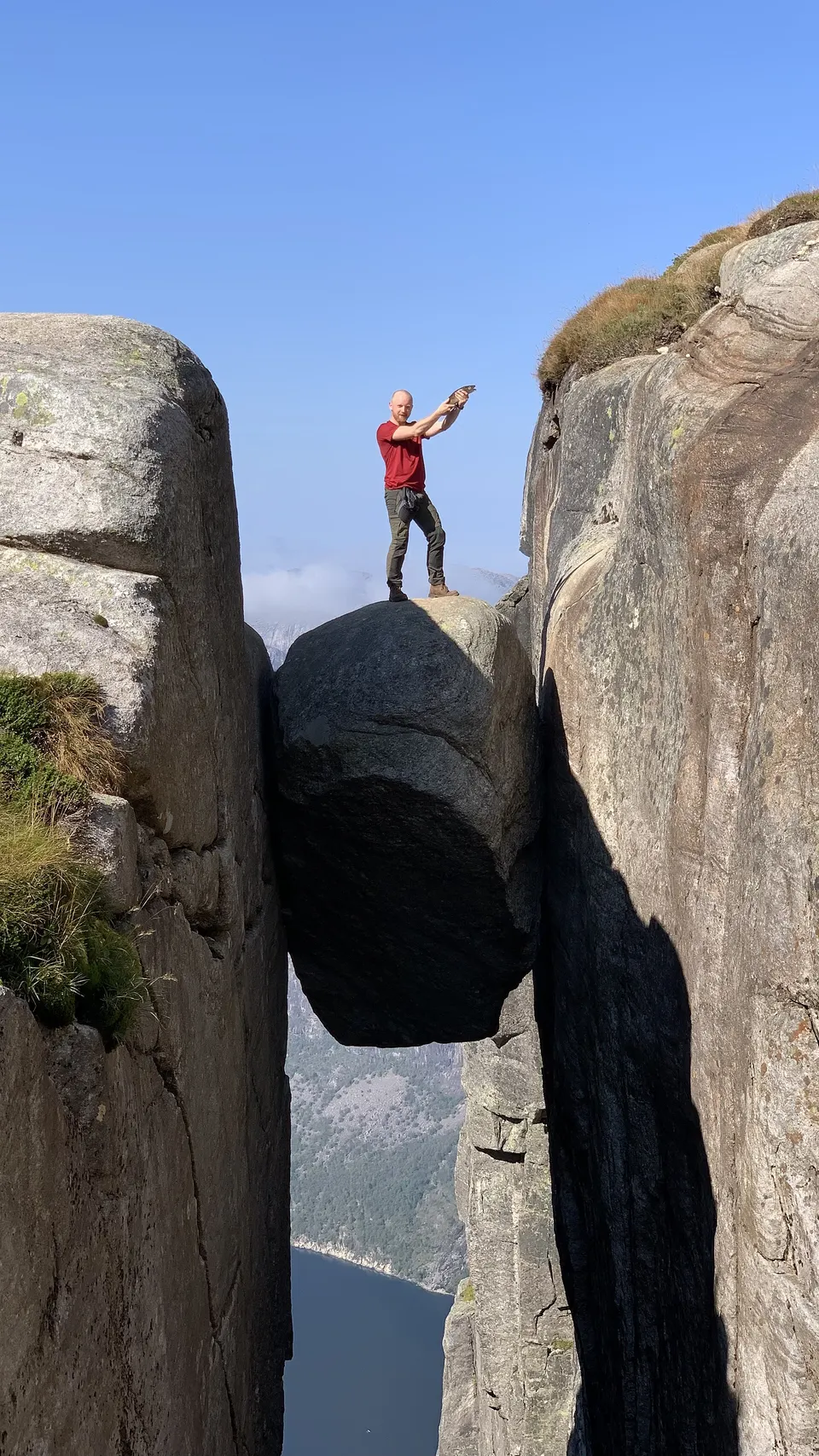 La roca redonda de Kjeragbolten encajada entre dos paredes de montaña sobre el abismo del Lysefjord.