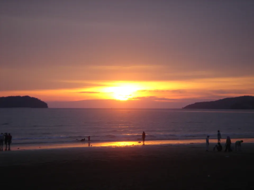 Cielo encendido con tonos rojizos y dorados en la célebre puesta de sol de la playa Tanjung Aru en Sabah.