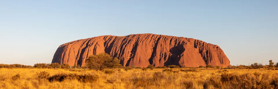 Primeras luces del alba iluminando las paredes de arenisca de Uluru desde el mirador Talinguru.