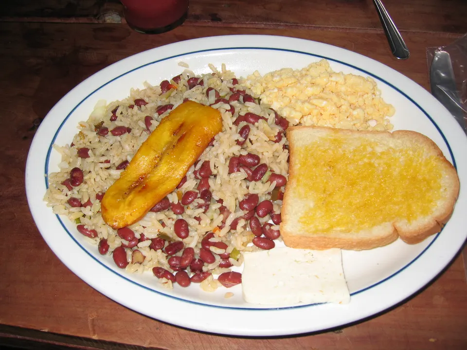 A Costa Rican Breakfast; rice and beans with eggs, toast, fried banana, and a slice of white cheese. en costa-rica