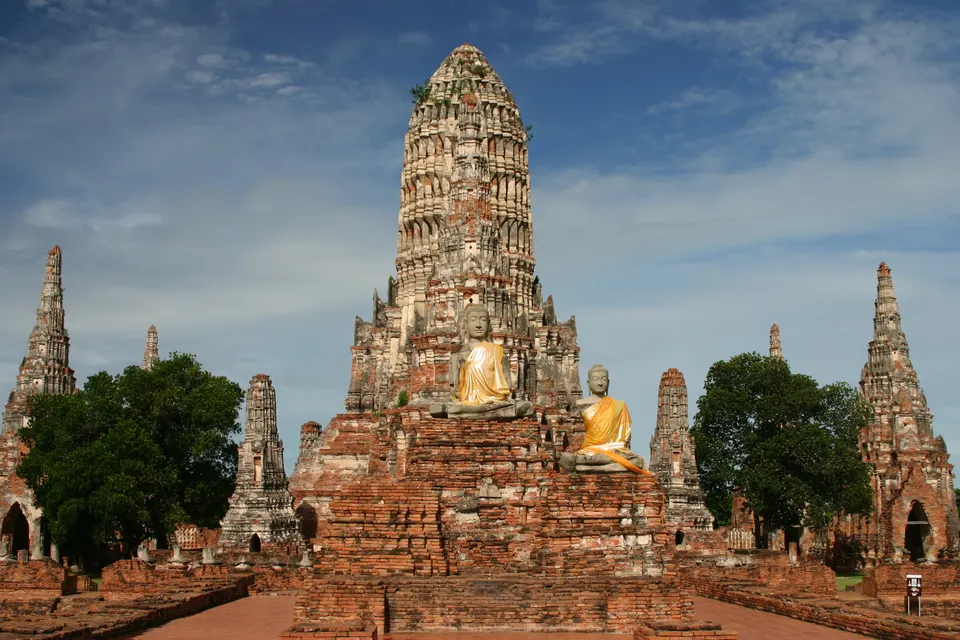 Prangs de ladrillo rojo y templos ancestrales iluminados al atardecer en el Parque Histórico de Ayutthaya.
