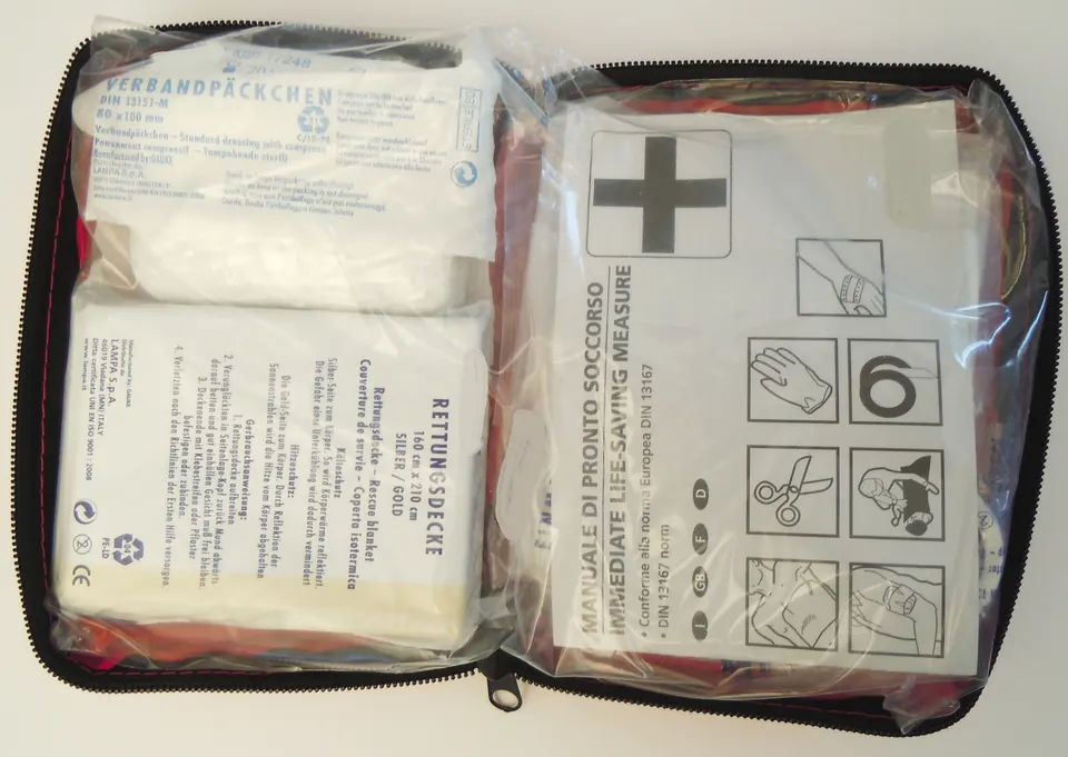 Kit de primeros auxilios abierto con gasas, vendajes y material médico de viaje.