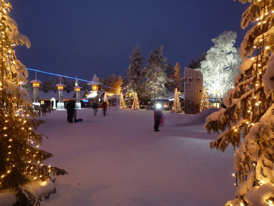 Cabañas de madera iluminadas bajo la nieve en la Aldea de Papá Noel en Rovaniemi, Círculo Polar.