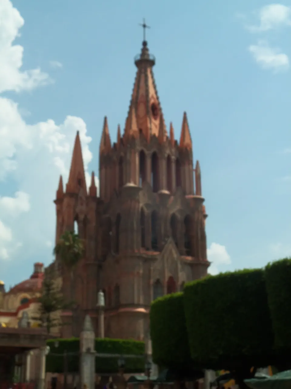 Fachada neogótica de cantera rosa de la Parroquia de San Miguel Arcángel con torres y pináculos.