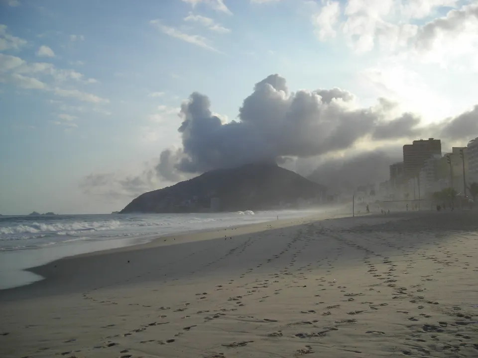 Playa de Ipanema con las siluetas escarpadas de los Morros Dois Irmãos al atardecer en Río de Janeiro.