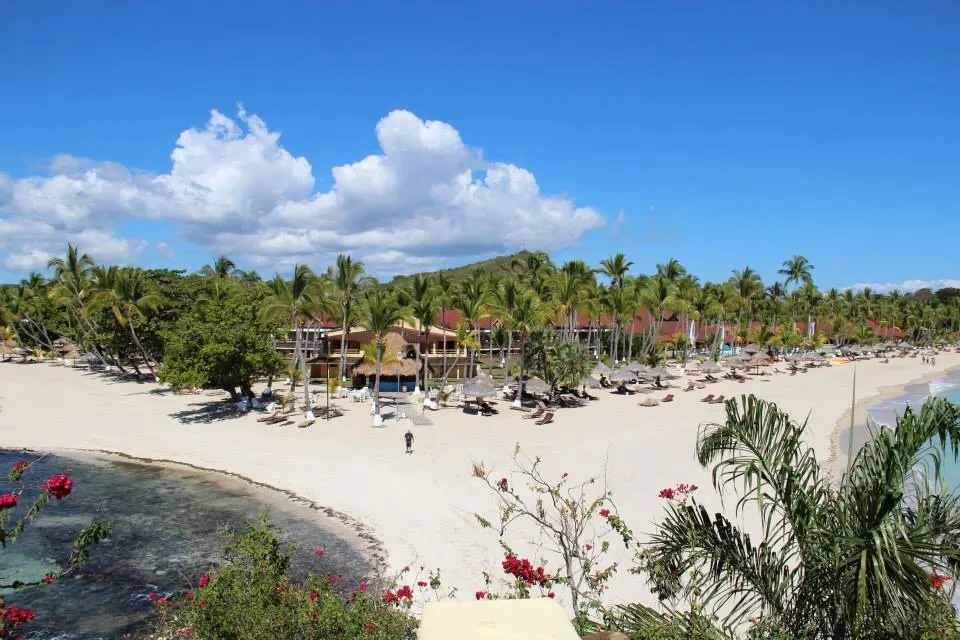 Aguas calmas y cocoteros inclinados sobre la blanca arena de la bahía de Andilana en Nosy Be.