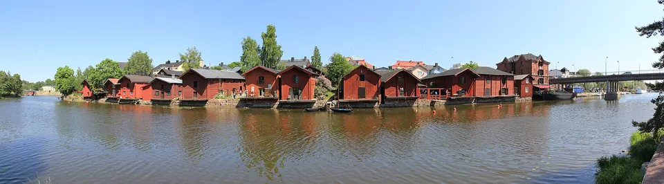 Almacenes portuarios de madera roja reflejándose en las aguas tranquilas del río Porvoonjoki.