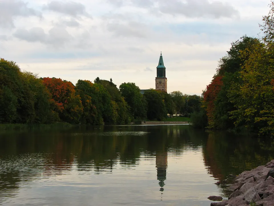 Imponente torre de ladrillo de la Catedral de Turku elevándose sobre los árboles a orillas del río Aura.