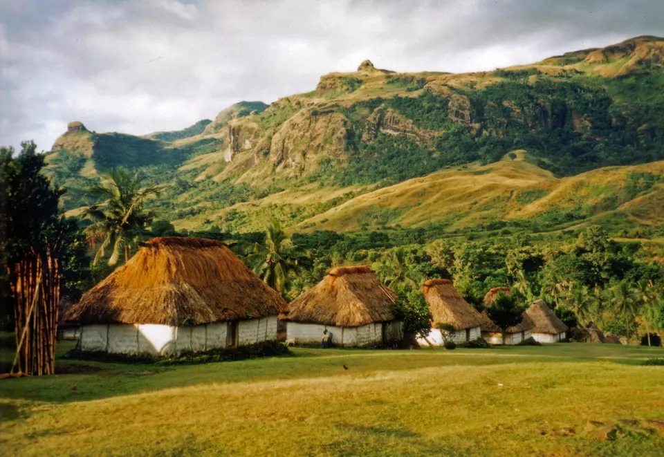 Aldea comunitaria tradicional fiyiana en las islas Yasawa con sus bures y palmeras circundantes.