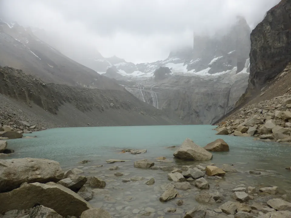 Las tres gigantescas torres de granito del Paine elevándose sobre la laguna glaciar de color verde lechoso