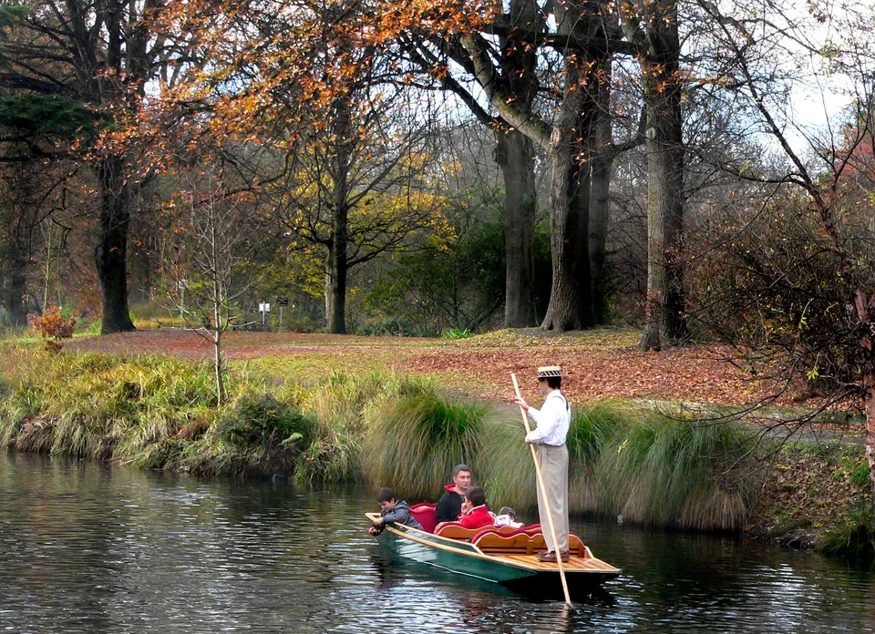 Barquero de época con sombrero de paja guiando una barca de fondo plano por el apacible río Avon.