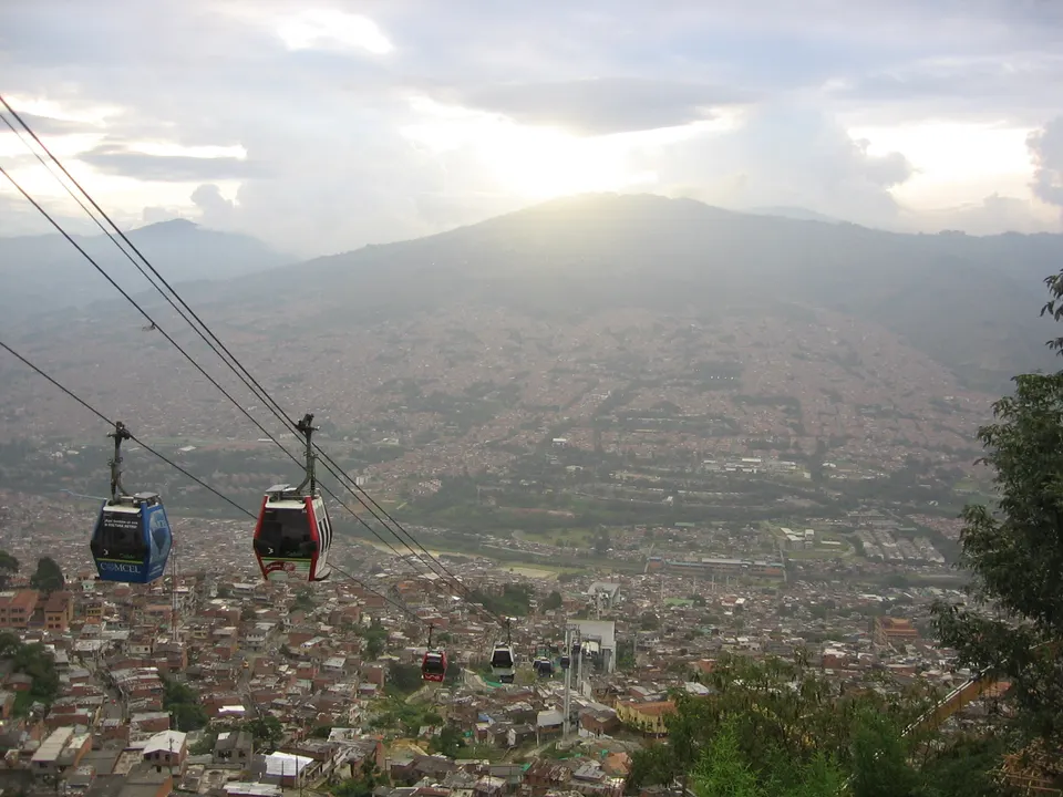 Cabinas del Metrocable de Medellín sobrevolando las laderas residenciales y las montañas del valle